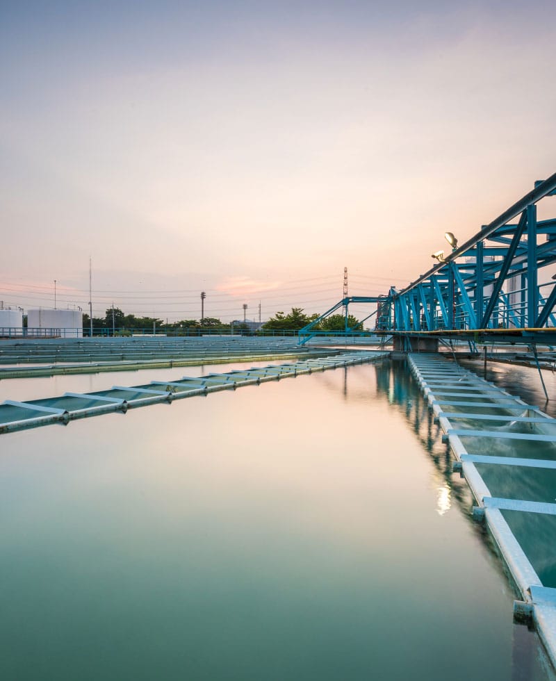 Gran instalación de tratamiento de aguas con estructuras azules y aguas tranquilas al atardecer