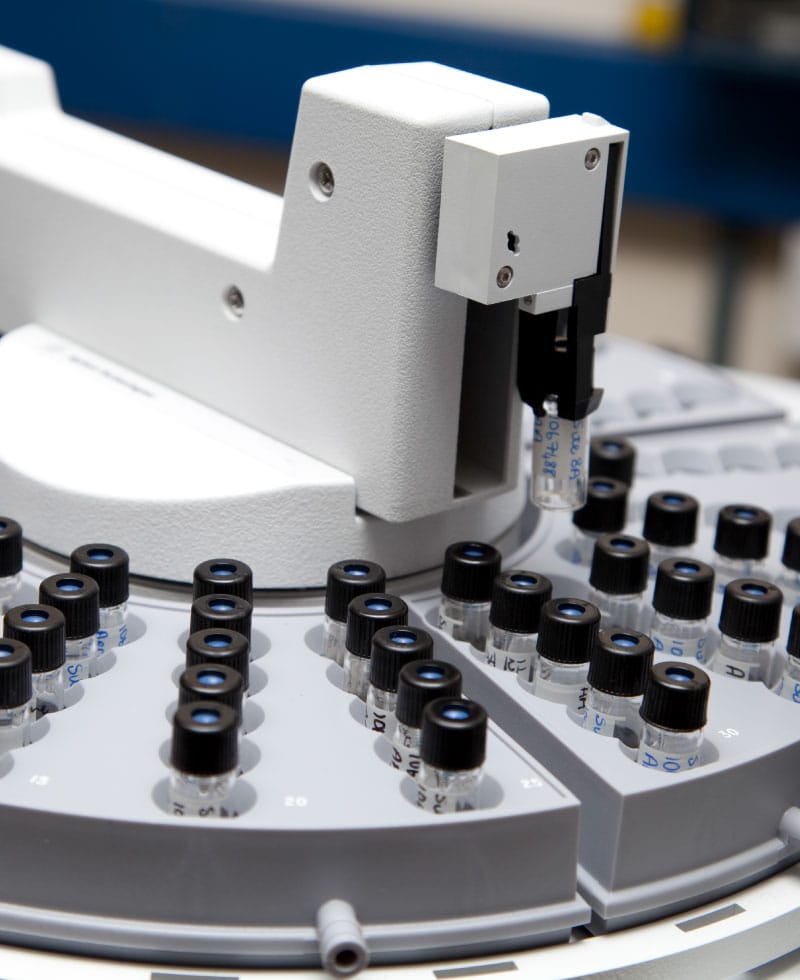 Primer plano de un analizador de cromatografía de gases con viales de muestras.